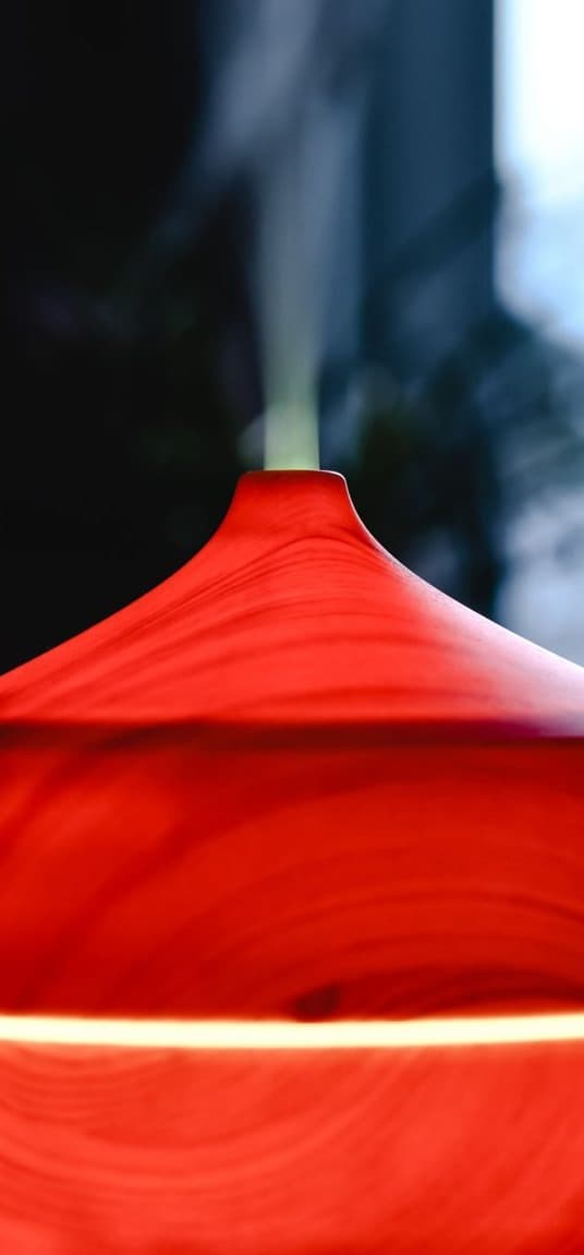 A wooden diffuser glowing red in a dim room